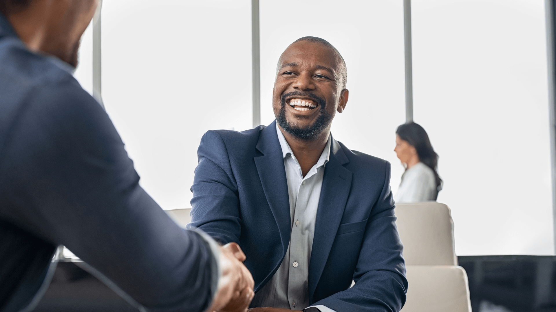Building Connections: Businessman Shaking Hands with a Client A businessman warmly shaking hands with a client in a professional setting.